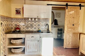A kitchen with a white countertop, a sink, and a stove. There are two woven baskets on the counter. - Holiday apartment with 1 bedroom (Carrapateria)