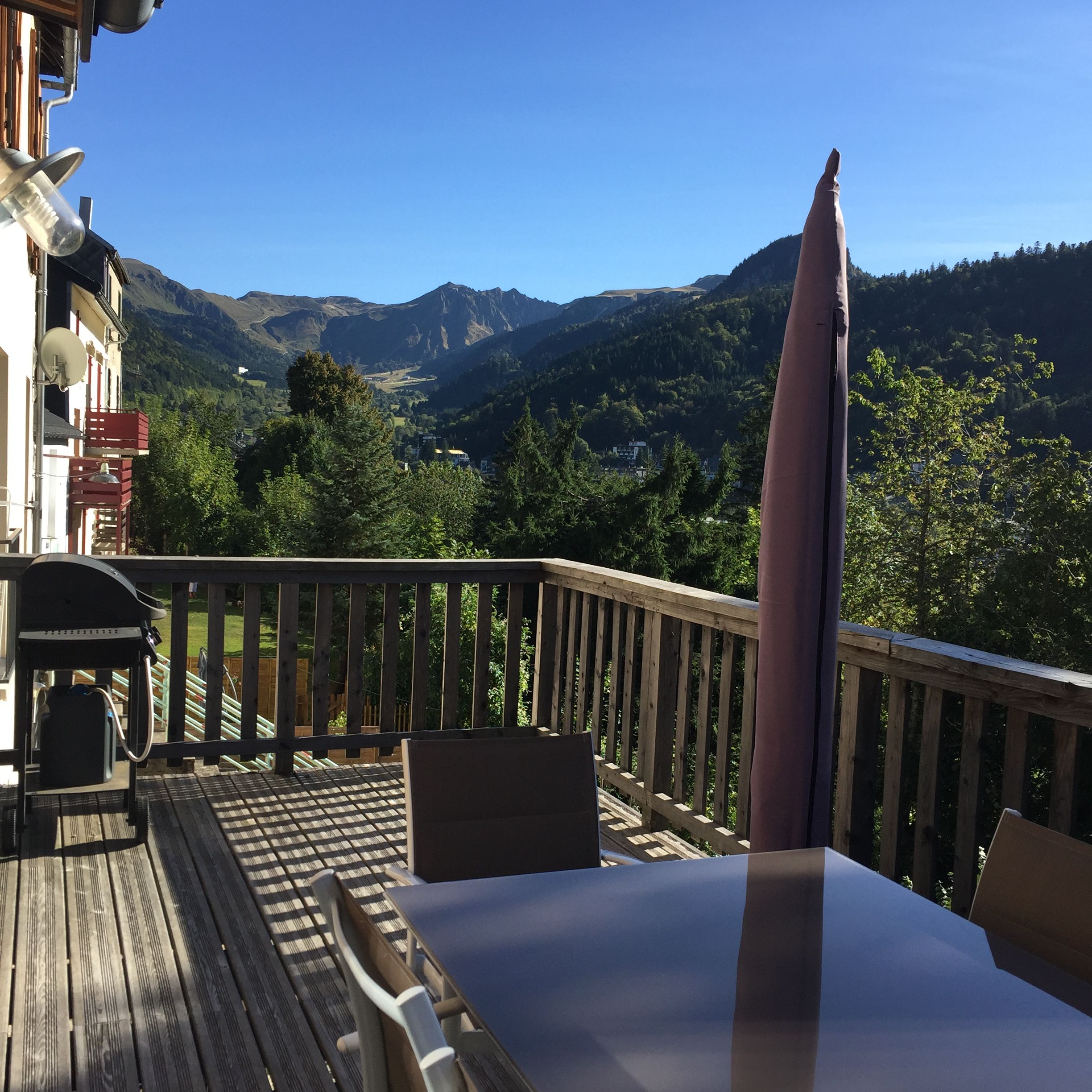 A deck with a table and chairs overlooking a mountainous landscape.