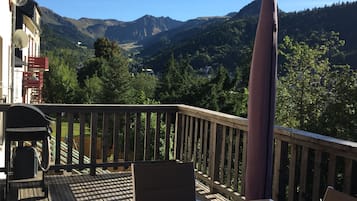 A deck with a table and chairs overlooking a mountainous landscape.
