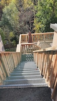 Una escalera de madera baja a un área de piscina con barandilla metálica de seguridad.