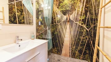 A bathroom with a white sink, a mirror, and a shower area with a rope bridge.