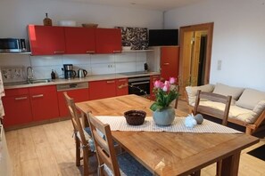 A kitchen with red cabinets, a wooden dining table, and a vase with flowers. - XL in the country house Rosmarin (Oschersleben)