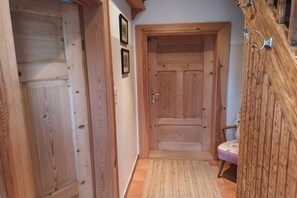 A wooden door with a handle, a small rug on the floor, and a chair in the corner. - XL in the country house Rosmarin (Oschersleben)