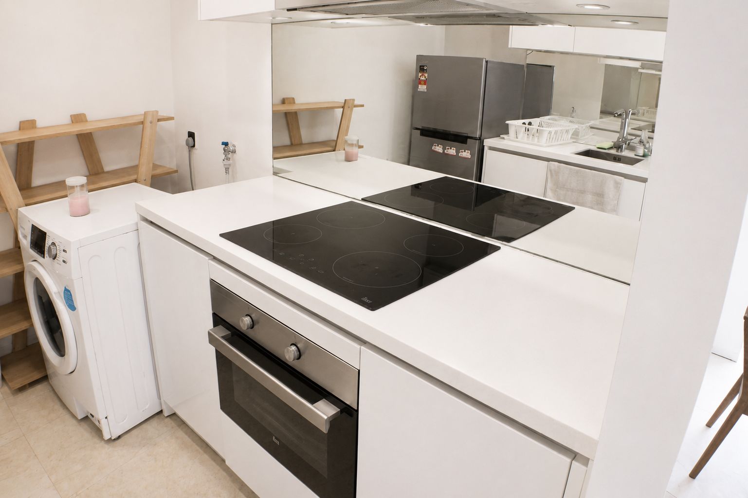 Une cuisine compacte équipée d’un lave-linge, d’un four et d’une plaque de cuisson à induction à deux foyers.