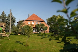 A two-story brick house with a red roof, surrounded by a grassy yard and trees. - Small and exquisite country gem (Darze)