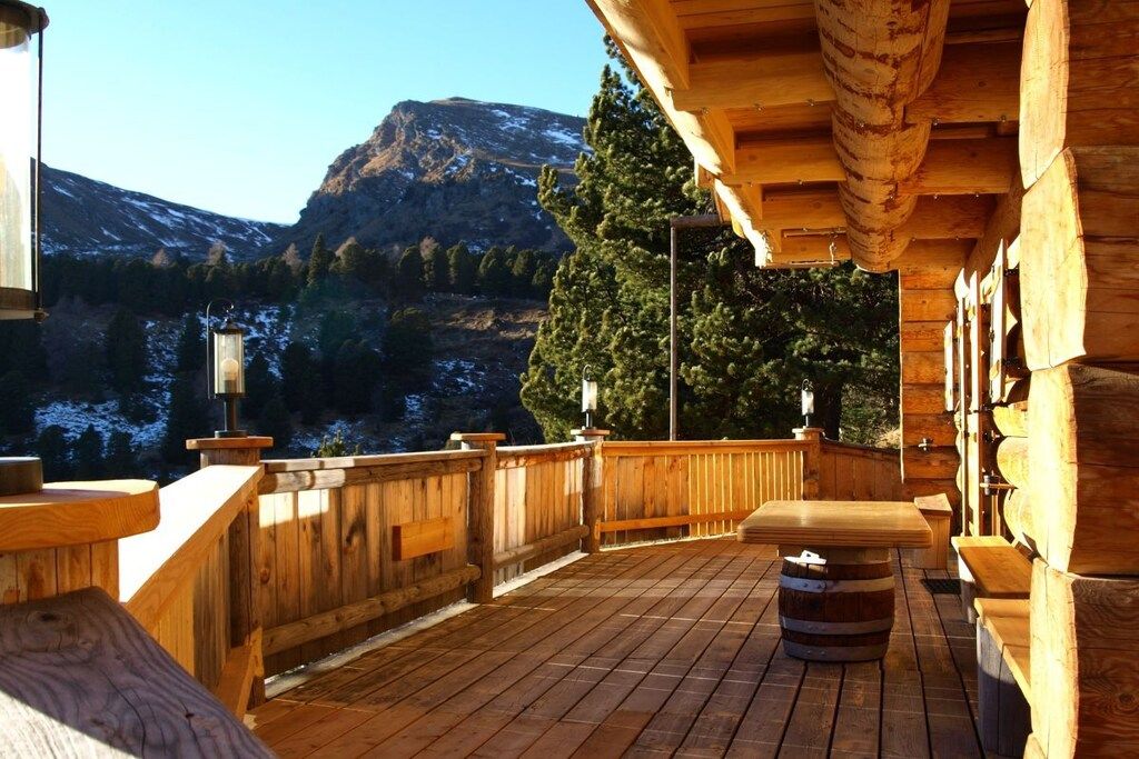Une terrasse en bois avec un banc en bois et un tonneau, offrant une vue sur un paysage montagneux.