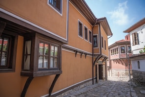A narrow cobblestone street with traditional European architecture, including a building with a wooden door and windows with shutters. - Delightful 7-bedroom house with AC in vibrant Plovdiv (Plovdiv)