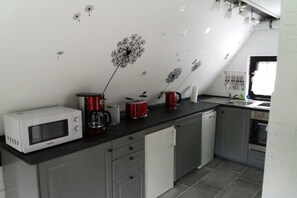 A kitchen with a microwave, coffee maker, and kettle on the counter, a dishwasher, and a sink. - Holiday home with 2 bedrooms (Schneverdingen)