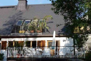 Un bâtiment à deux étages doté d’un balcon, d’une clôture blanche et surplombant un ciel dégagé.
