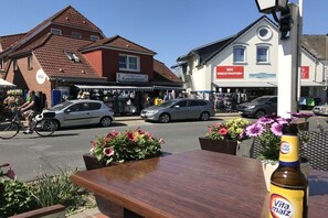 Een straatbeeld met winkels, een fiets en een fles Vita Malz bier.