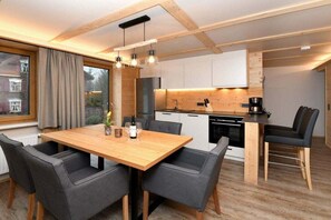 A modern kitchen with wooden cabinets, a dining table with chairs, and a coffee machine. - Holiday apartment in Au with swimming pool (Au)