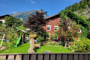 A residential area with a playground, a large tree, and a building with a red facade. - Holiday apartment in Au with swimming pool (Au)