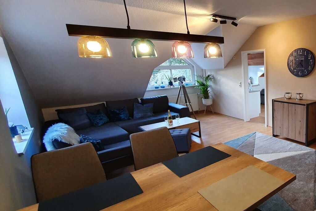 En moderne stue med sofa, spisebord og hængende lamper.