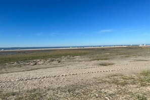 A beach with a clear sky, sandy terrain, and sparse vegetation. - Holiday home with 3 bedrooms (Wangerland)