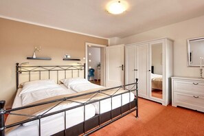 A bedroom with a metal bed frame, a white dresser, and a mirror. - Holiday apartment with 2 bedrooms (Garmisch Partenkirchen)