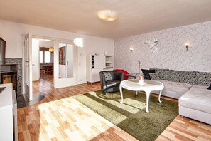 A modern living room with a sofa, a round coffee table, and a fireplace. - Holiday apartment with 2 bedrooms (Garmisch Partenkirchen)