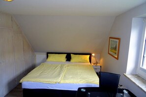 A bedroom with a bed, bedside table, lamp, and a window. - Holiday apartment with 1 bedroom (Westerland)