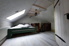 A room with a sloped ceiling, a bed with pillows, a wooden staircase, and a radiator. - Holiday home with 2 bedrooms (Byhleguhre)