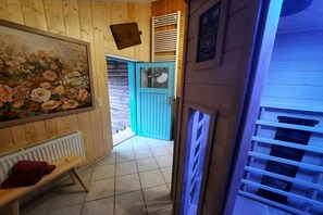 A wooden interior with a bench, a blue door, and a radiator. - Holiday home with 2 bedrooms (Byhleguhre)