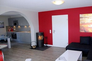 Ein gemütlicher Wohnraum mit Küchenzeile, Kamin und einer roten Akzentwand.