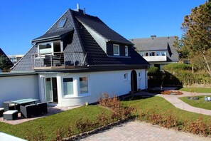 A two-story house with a balcony, a patio with outdoor furniture, and a well-maintained lawn. - Apartment in Westerland with swimming pool (Westerland)