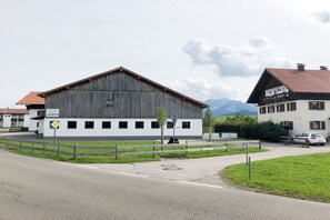 A building with a large wooden structure, a fenced area, and a road in front. - At the bricklayer's - gentian (Hopferau)