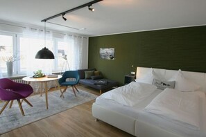 A modern bedroom with a bed, a sofa, a chair, a table, and a lamp. - Alpine Flair Holiday Apartment 101 Zeitgeist (Oberstdorf)