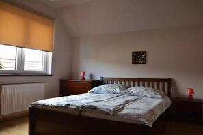 A bedroom with a bed, a window with blinds, a radiator, a nightstand, and a wall-mounted picture. - Holiday home with 3 bedrooms (Jelenia Gora)