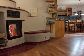 A living room with a fireplace, wooden flooring, and a dining area with a table and chairs. - Holiday apartment with 1 bedroom (Badenweiler OR Sehringen)