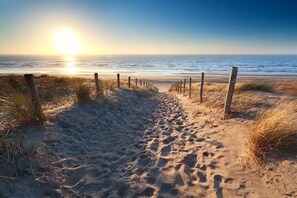 A sandy beach path leading to the ocean with a wooden fence on one side. - Duinweg 4a - Apartment A (Huisduinen)
