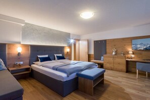 Ein modernes Schlafzimmer mit einem großen Bett, Nachttischen, einem Schreibtisch und einem Sessel.