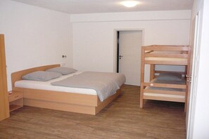 A bedroom with a single bed, a wooden bunk bed, a bedside table, and a door. - At the bricklayer's - Alpine rose (Hopferau)