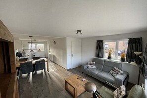 A modern living space with a dining area, a sofa, and a window with curtains. - including "Beach House by the Sea" (Zoutelande)