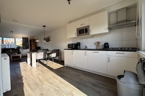 A modern kitchen with white cabinets, a microwave, and a stove. - including "Beach House by the Sea" (Zoutelande)