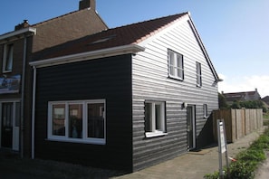 A two-story residential building with a dark facade and a red-tiled roof. - including "Beach House by the Sea" (Zoutelande)