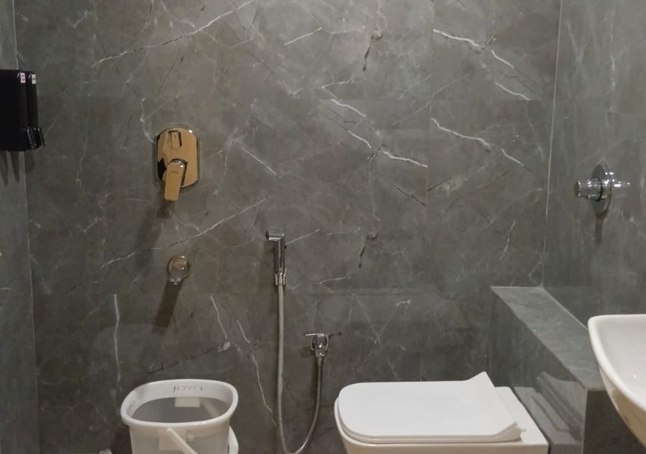 Une salle de bain avec un mur en marbre, des toilettes, un bidet et une douche.