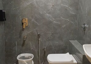 A bathroom with a marble wall, a toilet, a bidet, and a shower. - Hotel Prince Inn (Chandrapur)