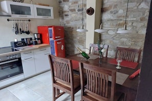 A kitchen with white cabinets, a red refrigerator, and wooden chairs around a dining table with a bottle and glass. - Holiday home in Ahr Valley with 1 bedroom (Ahrweiler)