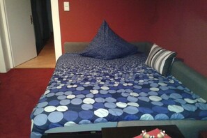 Ein Zimmer mit einem Bett, einem grünen Sofa und einem roten Teppich.