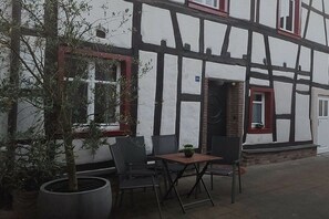 Il s’agit d’un bâtiment traditionnel à colombages doté d’un patio aménagé avec une table et des chaises.
