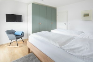 A bedroom with a bed, a wardrobe, a chair, and a television. - Holiday apartment in Juist with swimming pool (Juist)