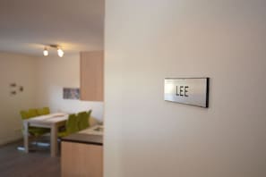 A room with a dining area, a bed, and a wall-mounted sign that reads 'LEE'. - Holiday apartment with 1 bedroom (Norden)