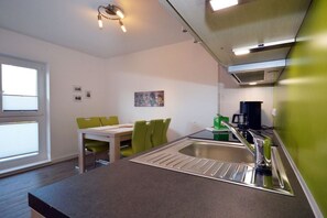 A compact kitchen with a sink, a dining area with chairs, and a window providing natural light. - Holiday apartment with 1 bedroom (Norden)