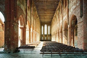 Un intérieur composé de rangées de bancs et de colonnes en briques en forme d’arc.