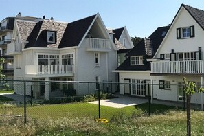 A residential area with multiple houses, each with a distinct architectural style, featuring balconies and a well-maintained lawn. - House of Georges Theunis (De Haan)