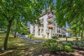 A multi-story residential building with balconies, surrounded by lush greenery and a well-maintained lawn. - Delbrück-Villen D112 Vacation Rental on the Beachfront in Heringsdorf (Heringsdorf (Seebad))
