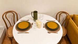 Une table de salle à manger ronde, avec deux assiettes de nourriture, une carafe et des bougies.