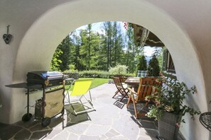 An outdoor patio with a grill, seating, and a view of a forest. - Holiday apartment with 1 bedroom (St. Ulrich a.P.)