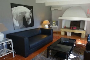 A living room with a sofa, a coffee table, a fireplace, and a wall-mounted artwork. - Holiday home with 1 bedroom (Saint-Gilles)