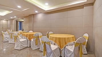 A conference room with round tables and chairs, each with a white cover and a yellow ribbon.
